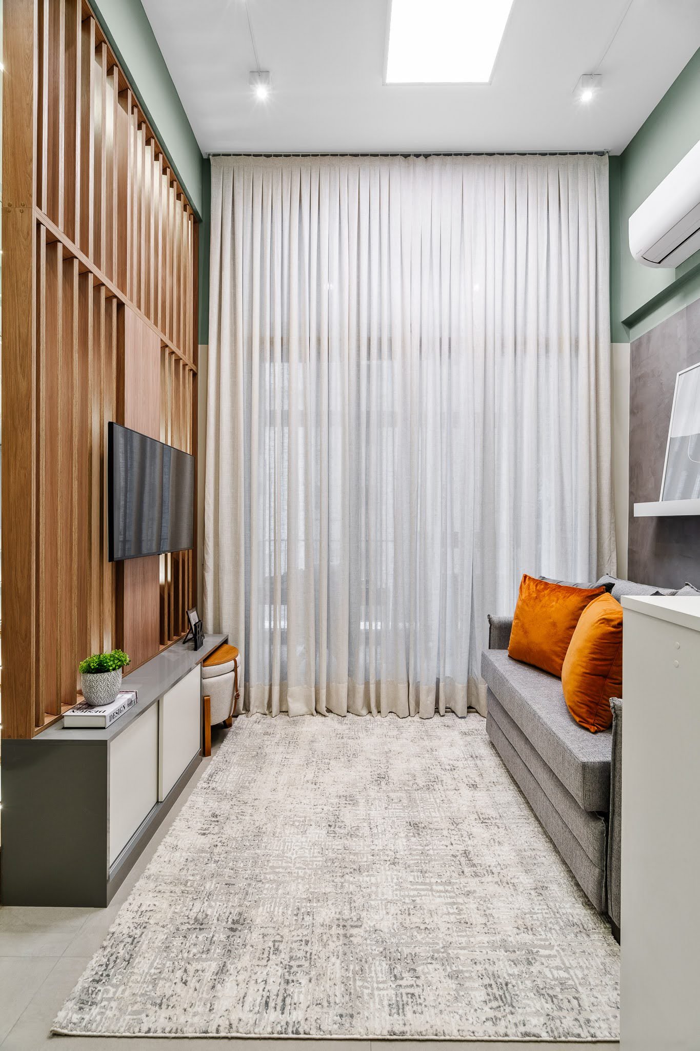 A neutral yet textured palette helps bring a sense of cohesion and calm to the living room of this small apartment. Shades of gray, white and light wood dominate, with layered finishes adding visual interest. Linen curtains have been used to soften the modern geometry, while various areas of the walls are painted in Suvinil’s Mantra, a muted gray with blue undertones. This subtle color shift helps define the vertical zones of the living area without overwhelming the space.