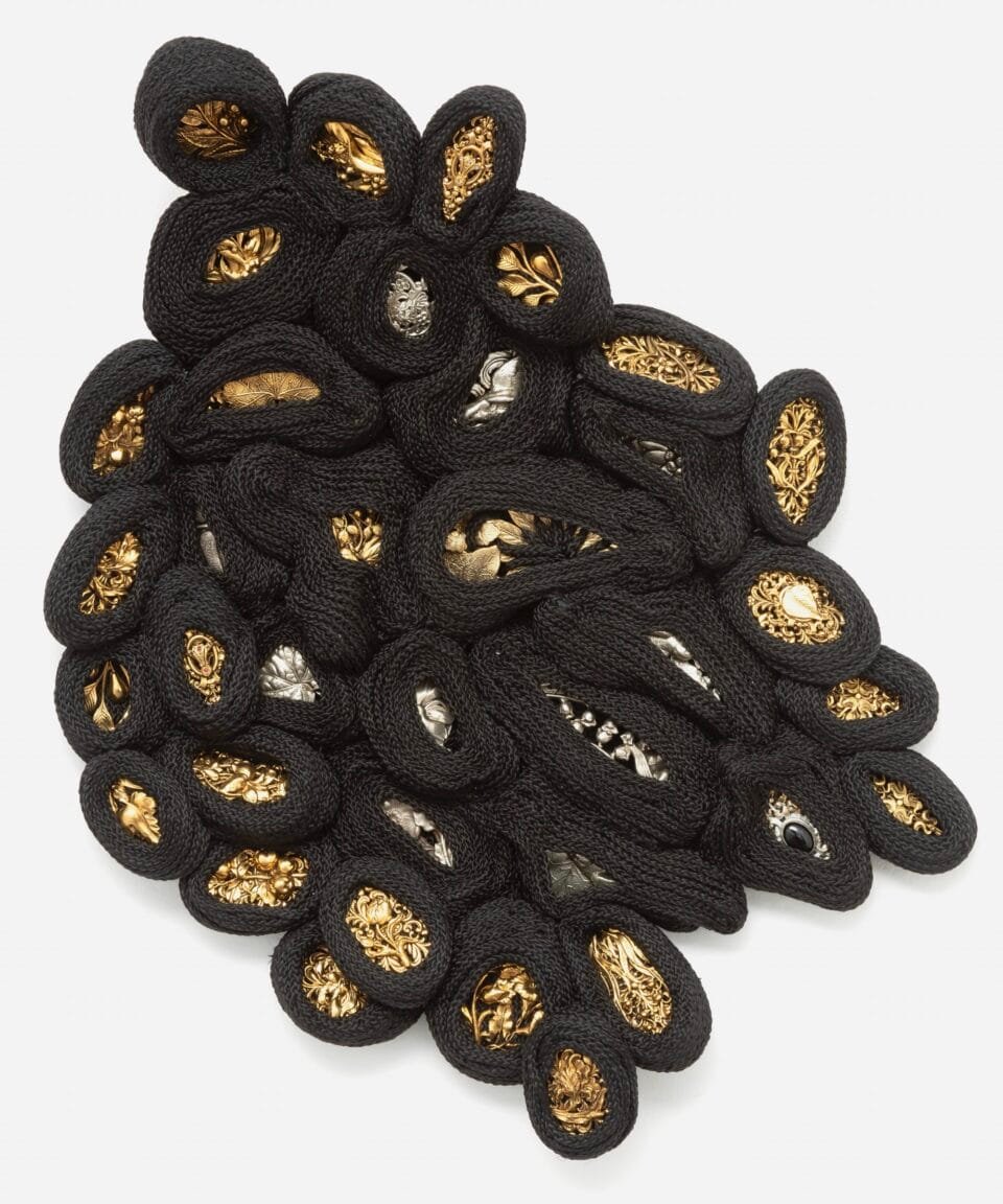 an artwork made from black cord, thread, and metal in the form of a cluster of small shapes or nodes