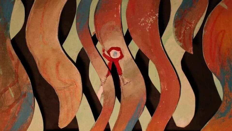 a paper cut assemblage of wavy patterns and a red figure with an eye in the middle