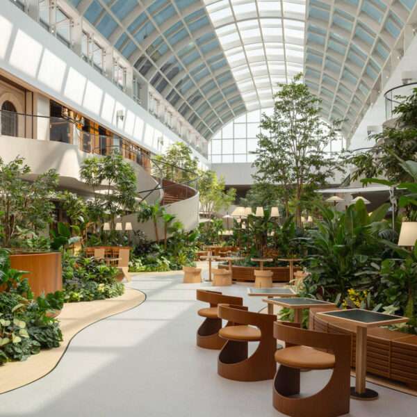 A transparent arched skylight transforms this indoor public garden space with natural light. Steel curves echo leaf veins while shifting sun patterns on the floor mimic moss growing in a greenhouse. A calming, nature-inspired design moment.