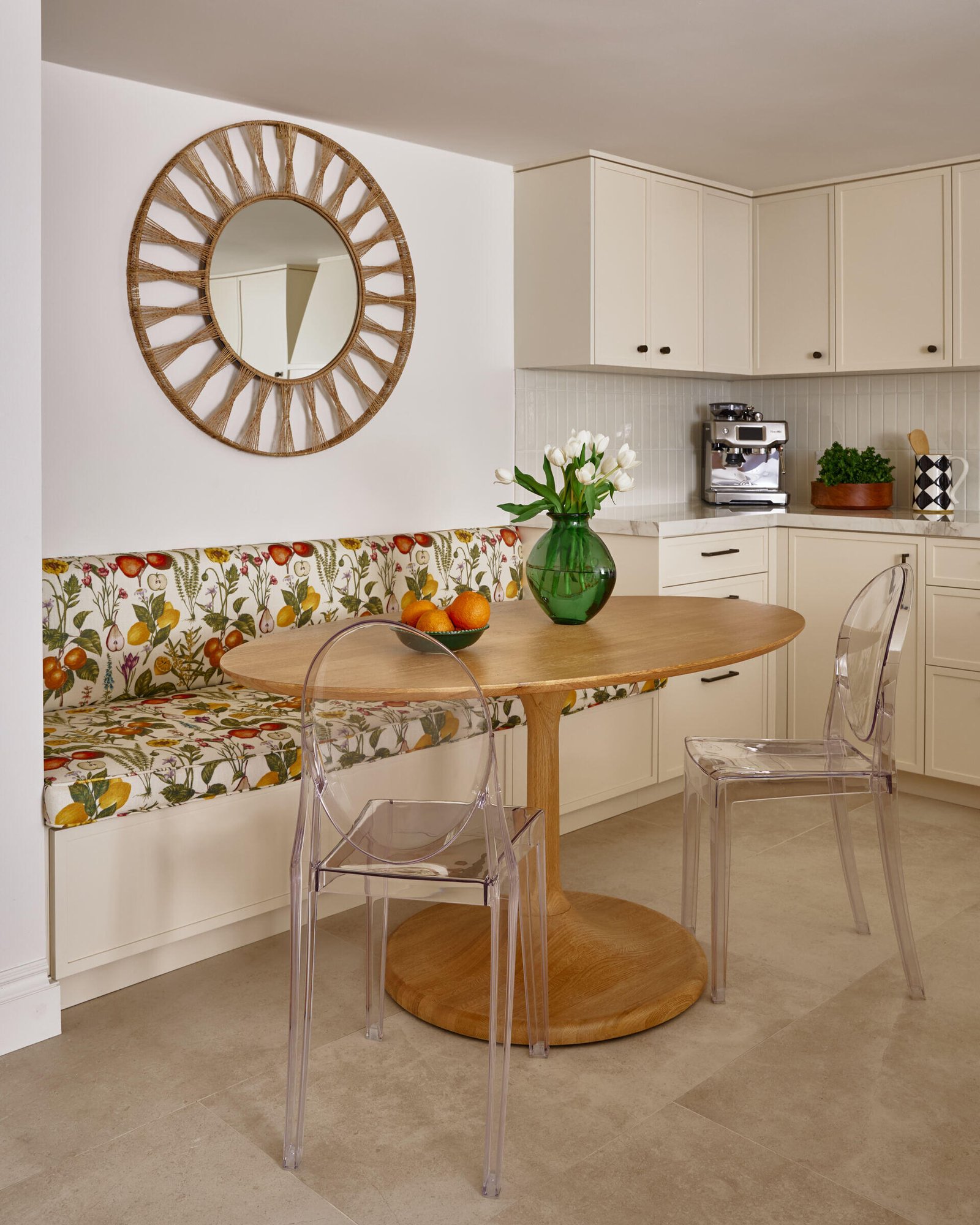 Tucked into the side of the kitchen, the breakfast nook is full of charm. A custom built-in bench in a botanical print wraps lines the wall, while the table has a pair of ghost chairs that keep the look light and airy. It’s a playful counterpoint to the kitchen’s quiet elegance.
