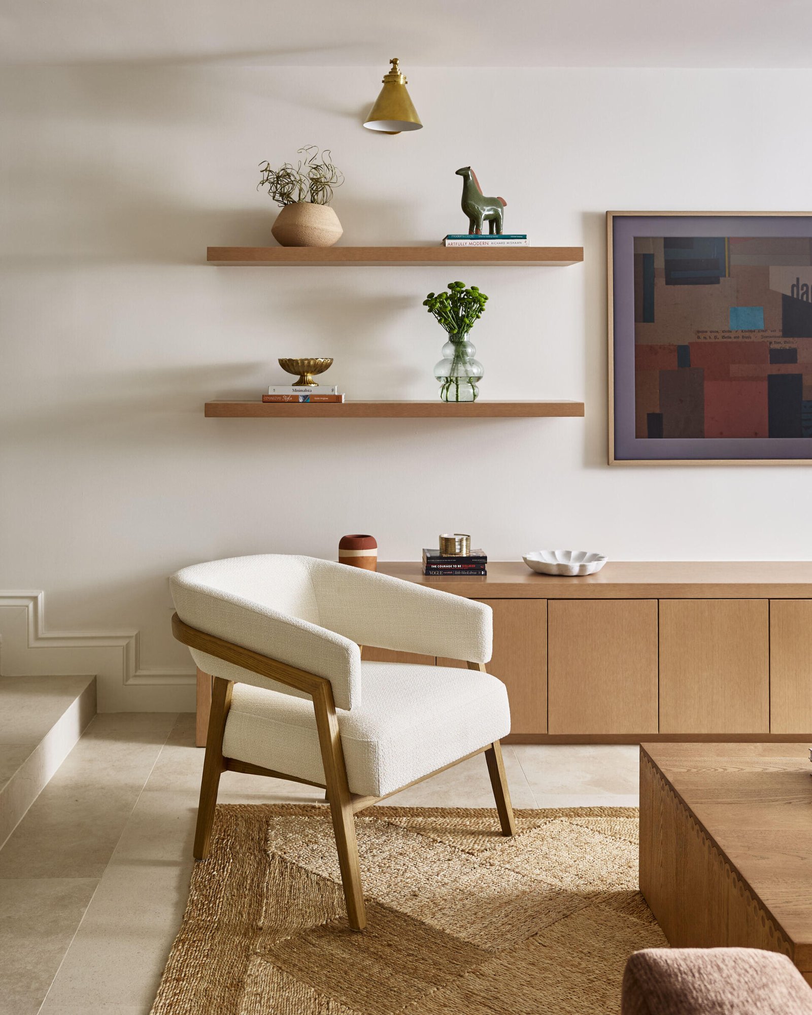 This modern living room features floating wood shelves curated shelves filled with art and pottery.
