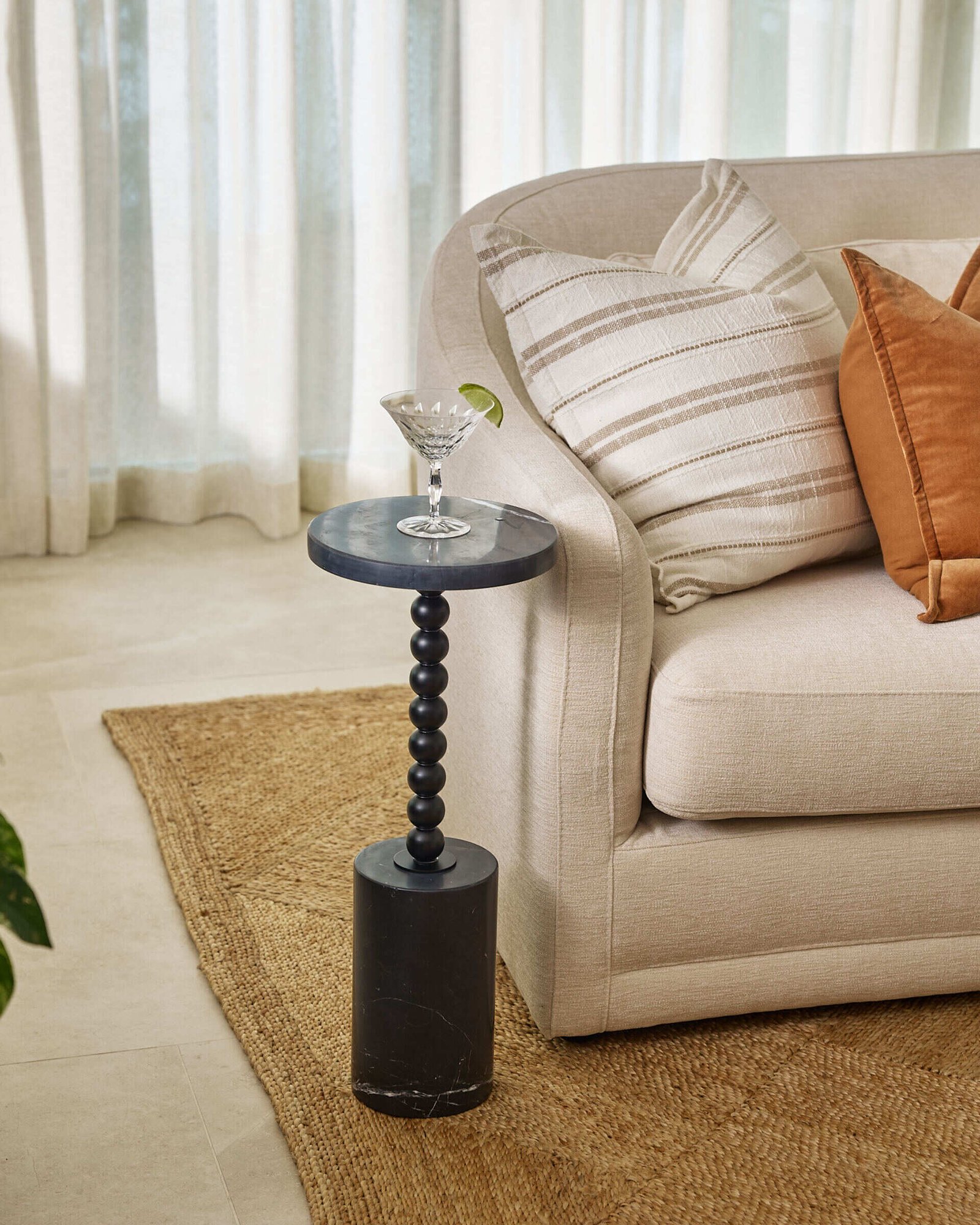 Warm neutrals and sculptural shapes make this more formal sitting room feel like a modern sanctuary. The soft cream sofa, styled with clay-toned pillows, sits against a wall of sheer drapes that gently filter daylight into the space. Two caramel velvet chairs add a rich, cozy texture, while the white marble coffee table introduces a cool, grounding contrast.