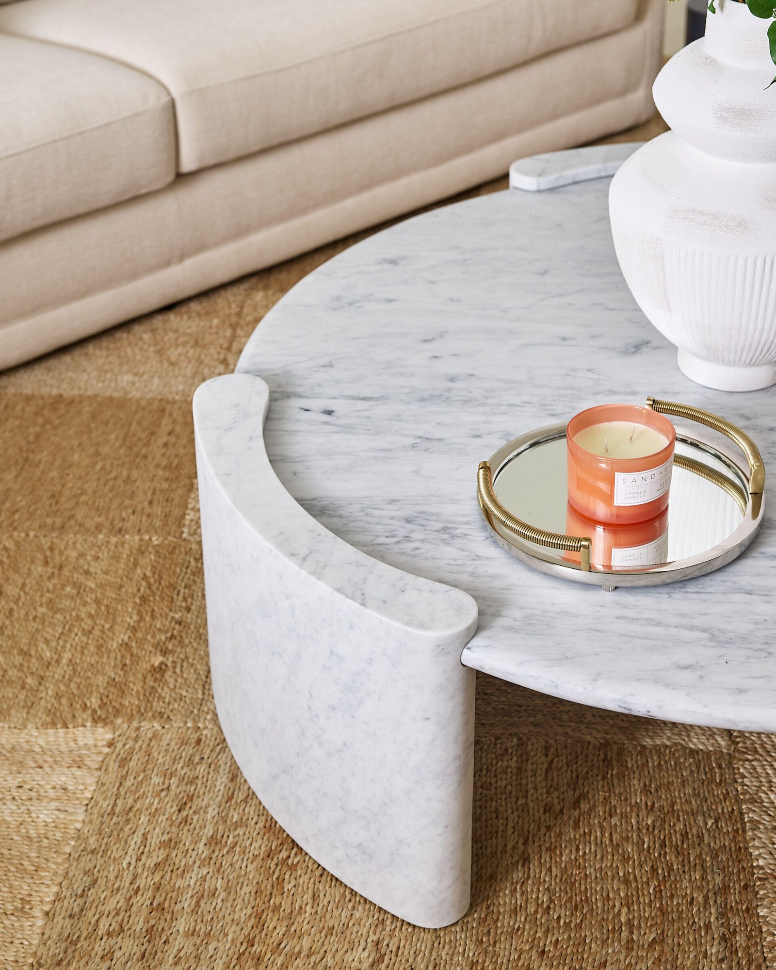 Warm neutrals and sculptural shapes make this more formal sitting room feel like a modern sanctuary. The soft cream sofa, styled with clay-toned pillows, sits against a wall of sheer drapes that gently filter daylight into the space. Two caramel velvet chairs add a rich, cozy texture, while the white marble coffee table introduces a cool, grounding contrast.