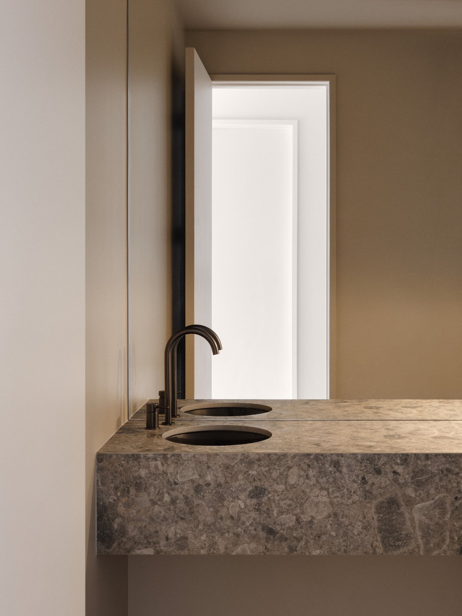 This powder room channels quiet luxury through rich materials and clean lines. A floating stone vanity with soft veining anchors the space, paired with a round basin and black faucets. Taupe walls and a large mirror create a calm, open feel, while subtle textures and refined details make the small room feel serene and indulgent.