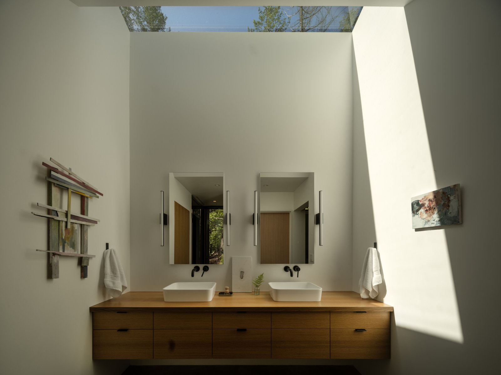 The primary bathroom finds quiet privacy behind an old-growth stump, making the daily act of bathing a moment of intimacy with the forest. Its placement invites occupants to observe the subtle changes in moss, bark, and filtered light, turning a simple ritual into a sensory connection with the land.