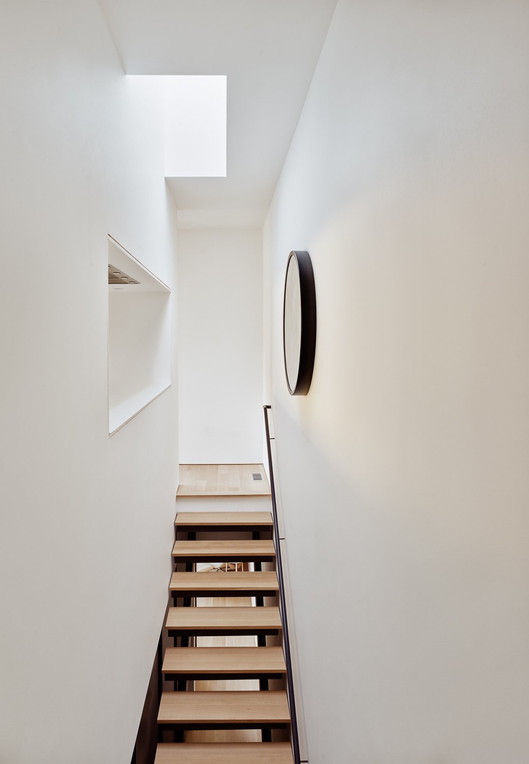The stairs are a crucial vertical link in this tall, narrow structure, but they don’t feel like an afterthought. They bring in natural light and act as a subtle divider between the more social upper floors and the restful, private quarters below.