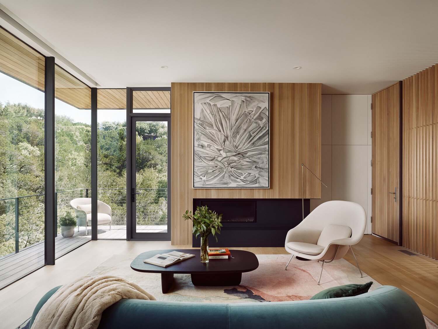 At the top of the home, the living room feels like it’s floating in the trees. Thanks to the upside-down layout, this space benefits from uninterrupted treetop views and natural light from multiple angles. The materials are simple but considered, with just enough texture and tone to keep the space feeling warm and grounded.