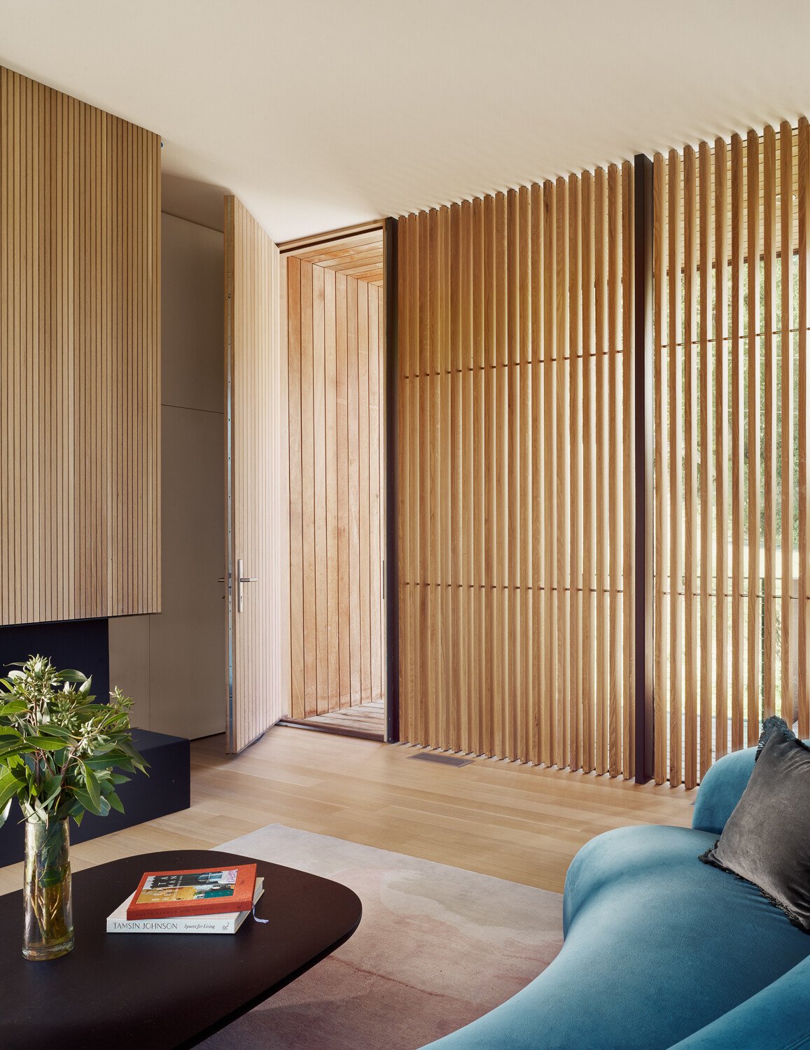 At the top of the home, the living room feels like it’s floating in the trees. Thanks to the upside-down layout, this space benefits from uninterrupted treetop views and natural light from multiple angles. The materials are simple but considered, with just enough texture and tone to keep the space feeling warm and grounded.
