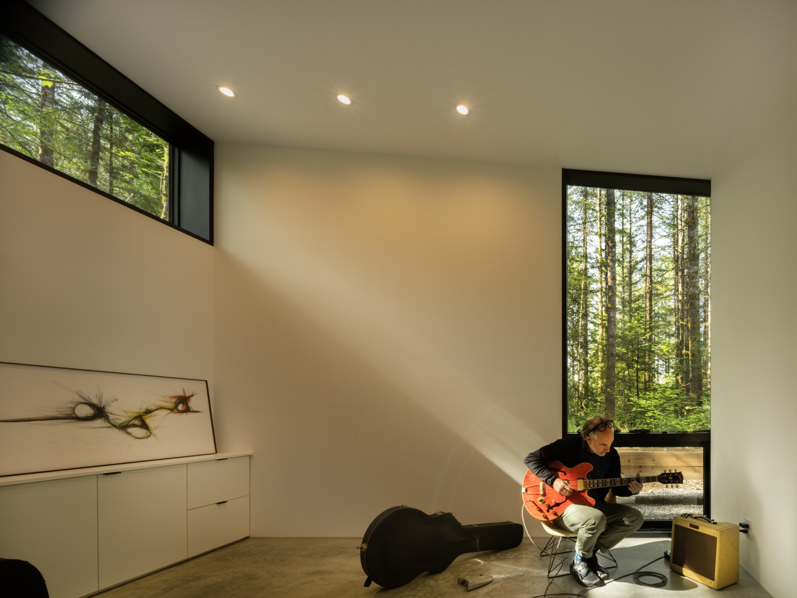 Tall windows bring in steady natural light, illuminating the polished concrete floors and pale walls of the music room. 