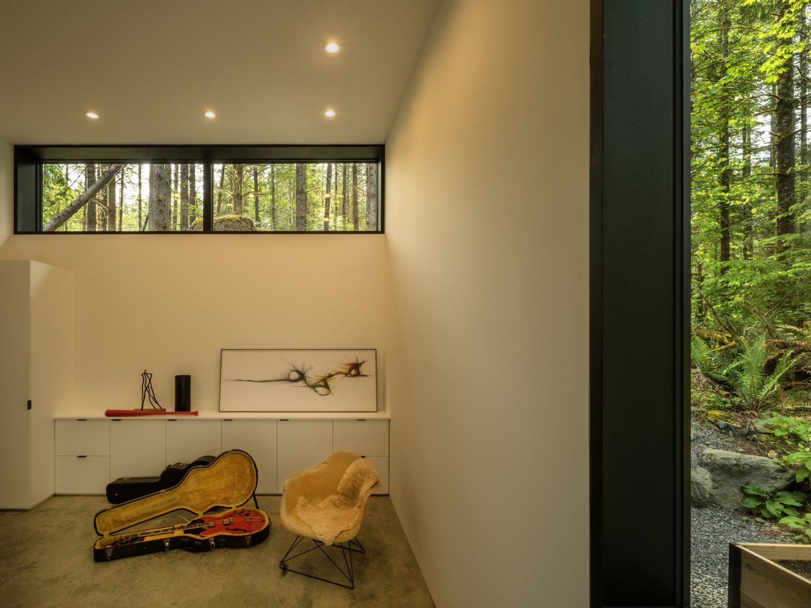 Tall windows bring in steady natural light, illuminating the polished concrete floors and pale walls of the music room. 