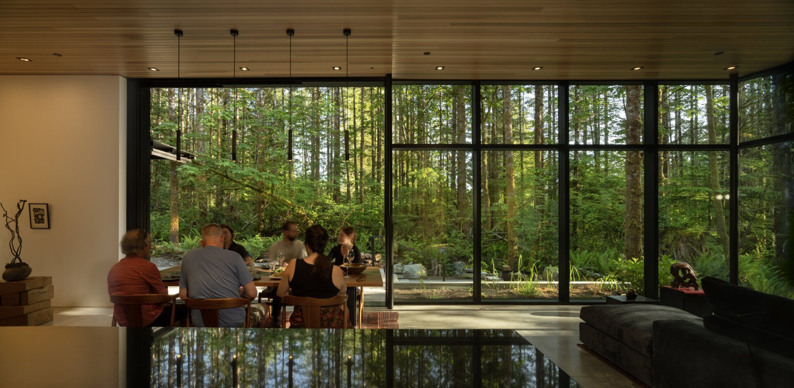  Indoor-outdoor dining made effortless. The patio and dining area open directly to the forest, with a shared material palette that connects meals to nature.