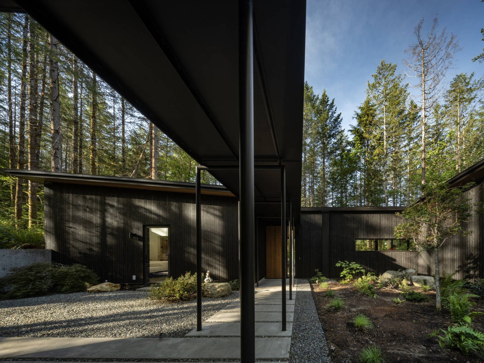 This quiet forest entryway blends wood, stone, and glass to create a seamless transition between outdoors and in.