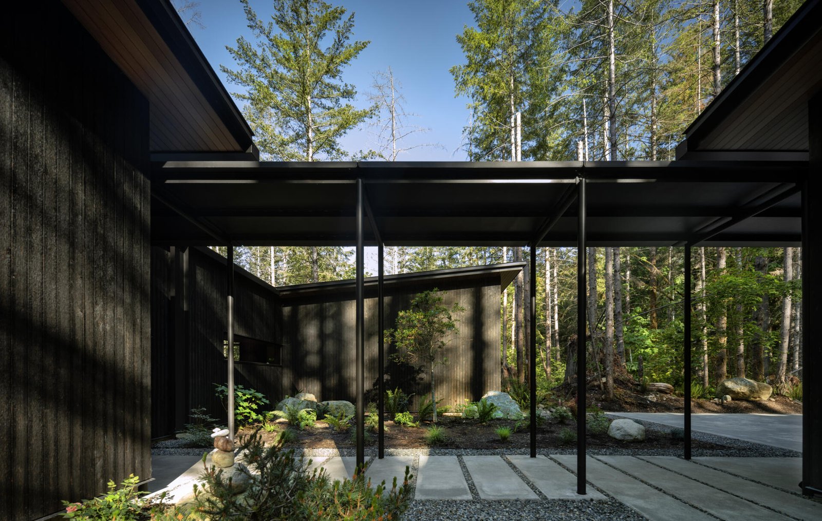 This quiet forest entryway blends wood, stone, and glass to create a seamless transition between outdoors and in.