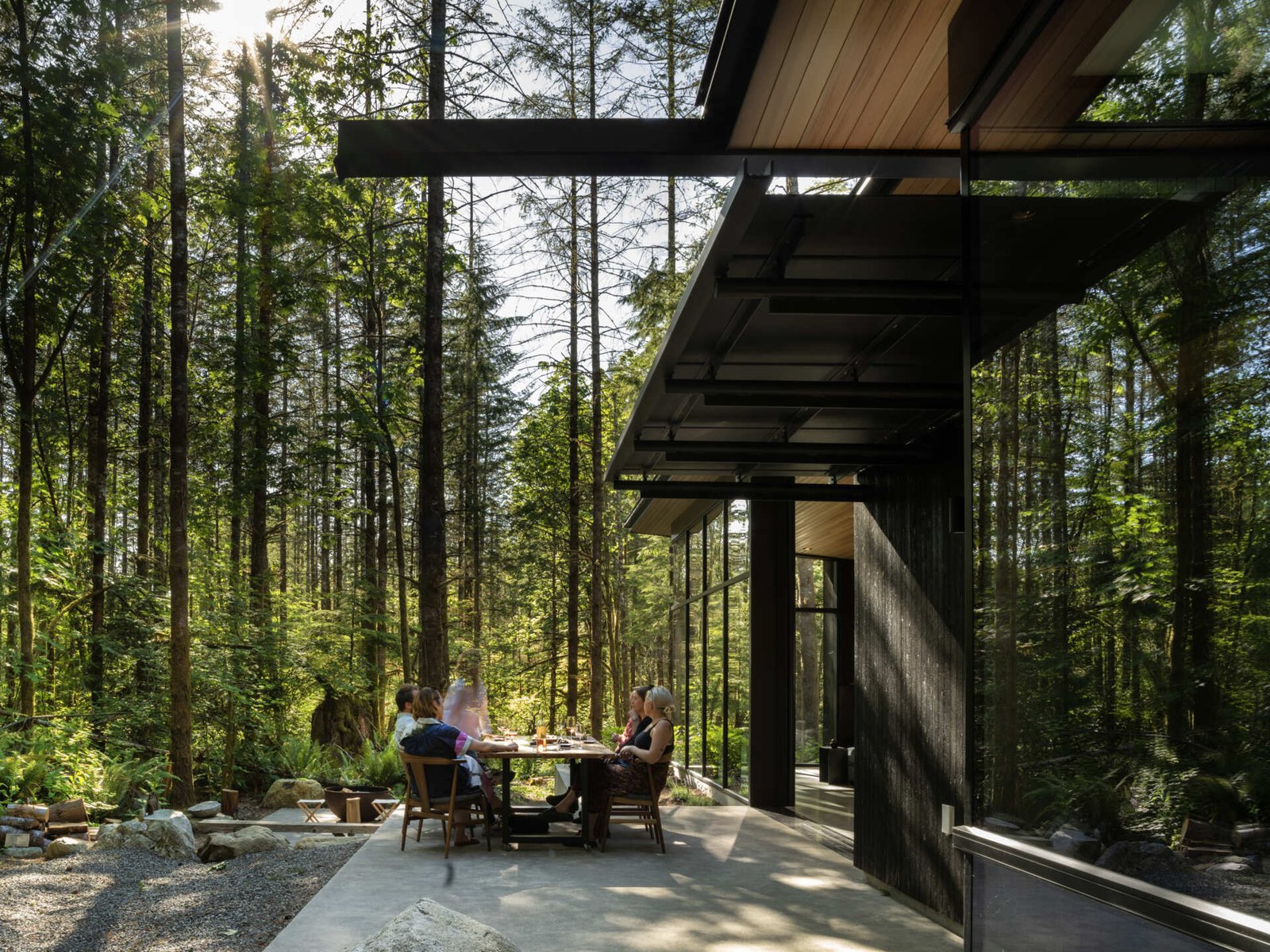 Indoor-outdoor dining made effortless. The patio and dining area open directly to the forest, with a shared material palette that connects meals to nature.