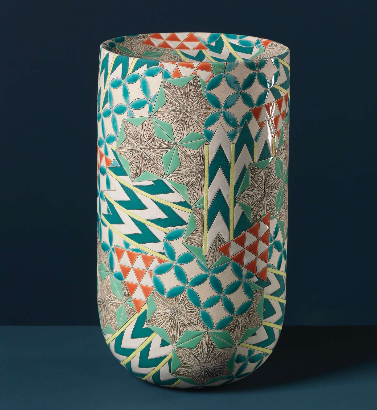 a colorful, geometrically patterned, cylindrical ceramic form