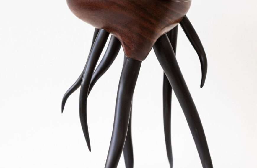 a wooden sculpture by Donald Wasswa with an abstract, sea creature-like form with long tentacles