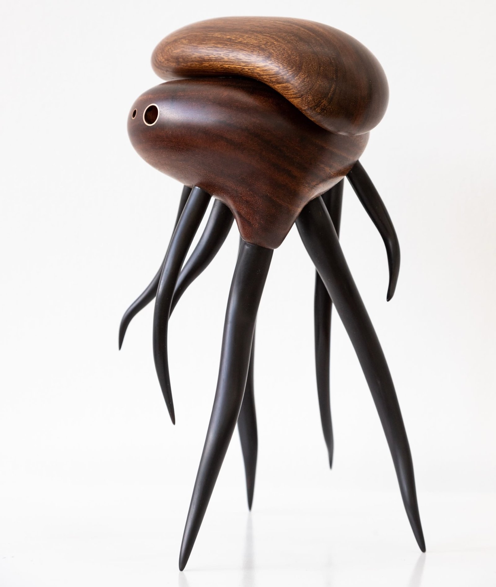a wooden sculpture by Donald Wasswa with an abstract, sea creature-like form with long tentacles