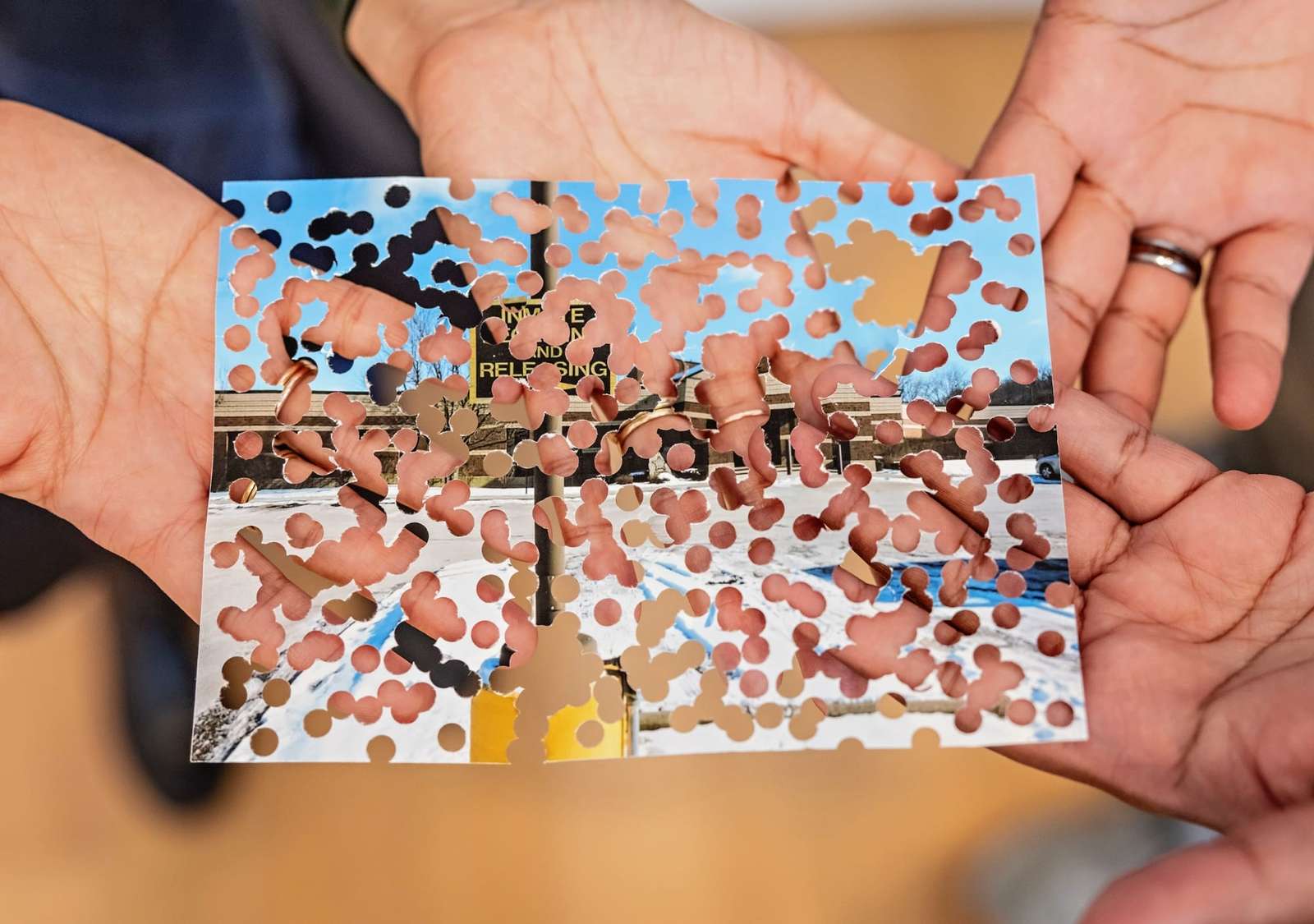 hands holding an image with innumerable punched holes