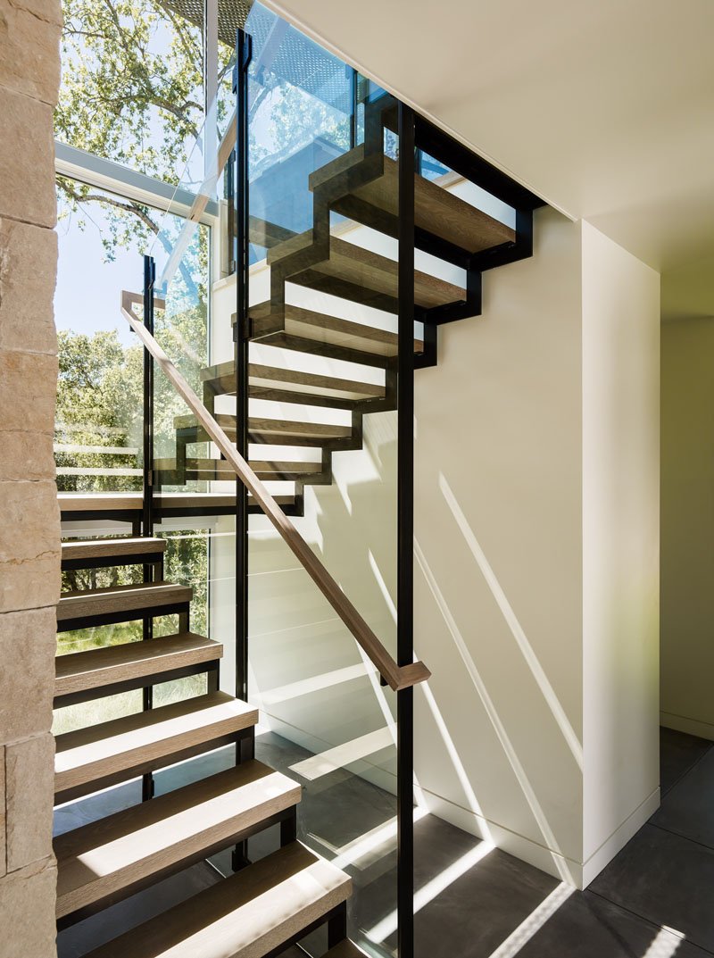 Wood-and-steel stairs lead to sunlit spaces and private guest suites connected by covered walkways for comfort and privacy.