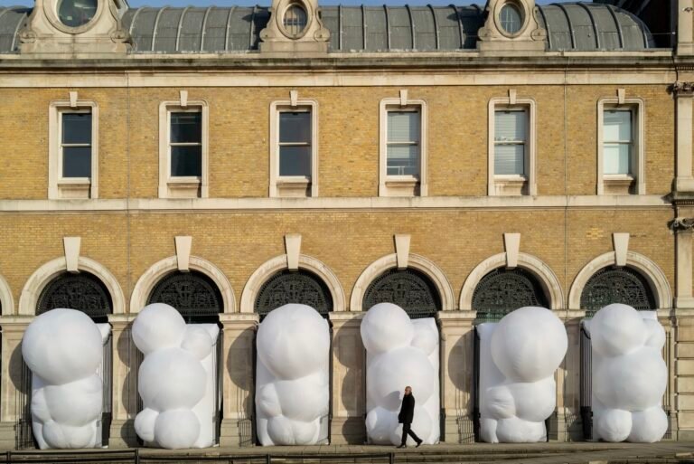 a series of large, white, bulbous, inflatable shapes designed by Steve Messam that stick out of an arched arcade on the first level of a brick building