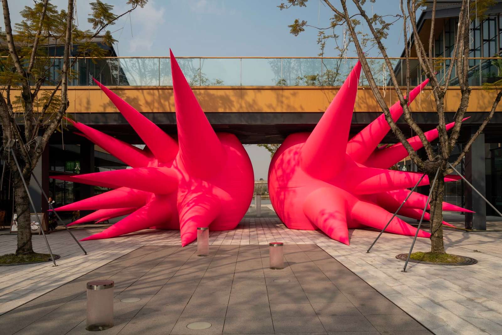 a large-scale inflatable sculpture installation by Steve Messam of two symmetrical, red, spiked forms wedged under a bridge