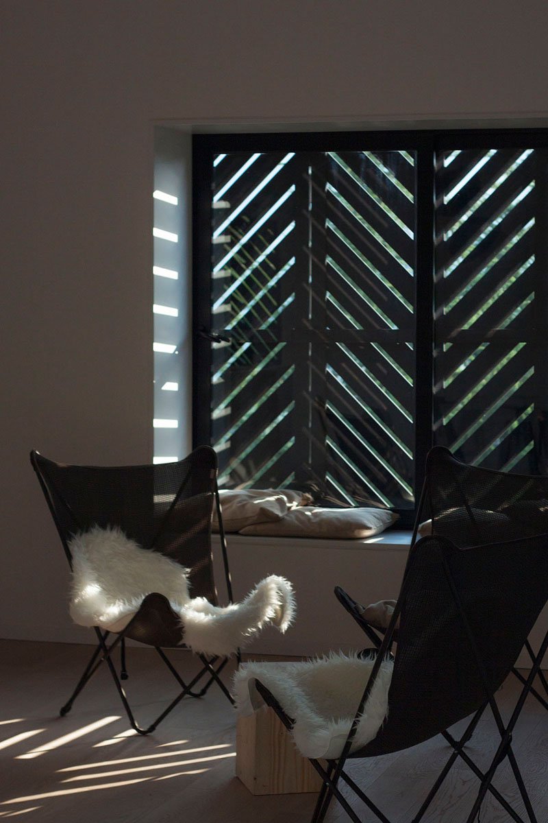 From indoors, the shutters reveal their diagonal pattern when closed, bringing the bold language of the facade into the interior while controlling light and privacy.