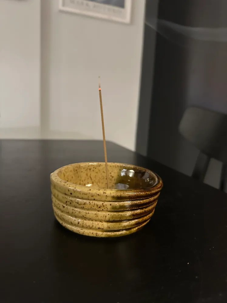 Incense stick in a ceramic bowl on a black table.