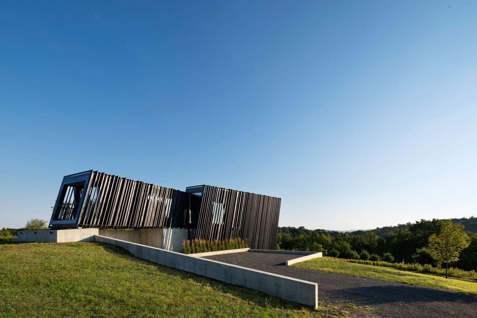 Wrapped in charred timber and set on a concrete base, this sculptural hillside home stands as a minimalist landmark in New York’s Hudson Valley.
