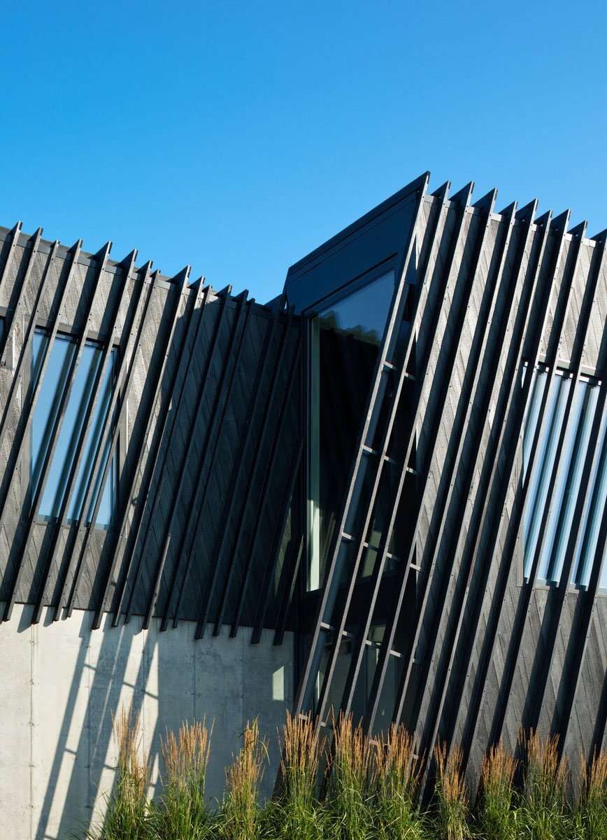 Wrapped in charred timber and set on a concrete base, this sculptural hillside home stands as a minimalist landmark in New York’s Hudson Valley.