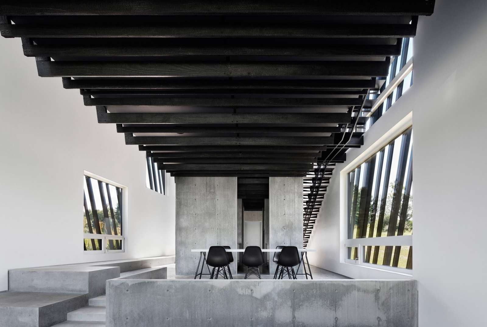 Matte-black cabinetry and a crisp black-and-white dining space define this modern kitchen, sleek, simple, and quietly luxurious.