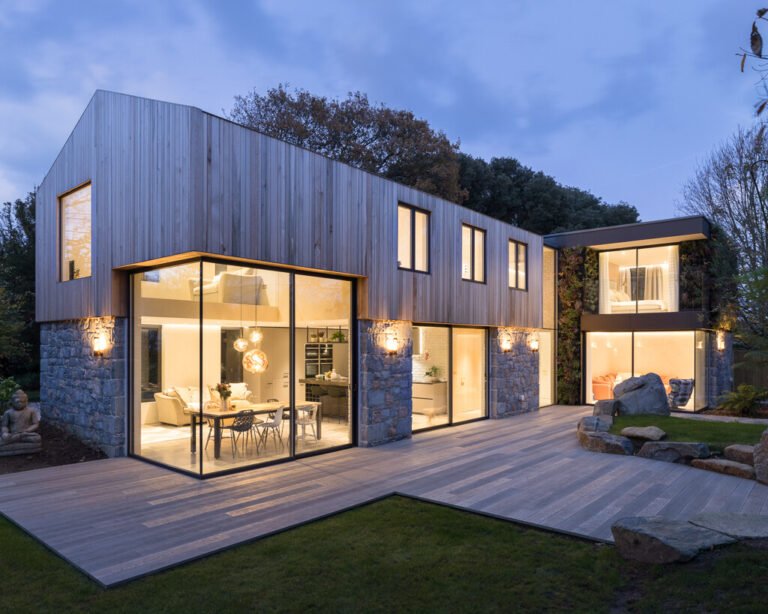 This modern home is wrapped in Guernsey granite, cedar cladding, and a living wall with 13 native species that soften the structure and blend it into the forested setting.