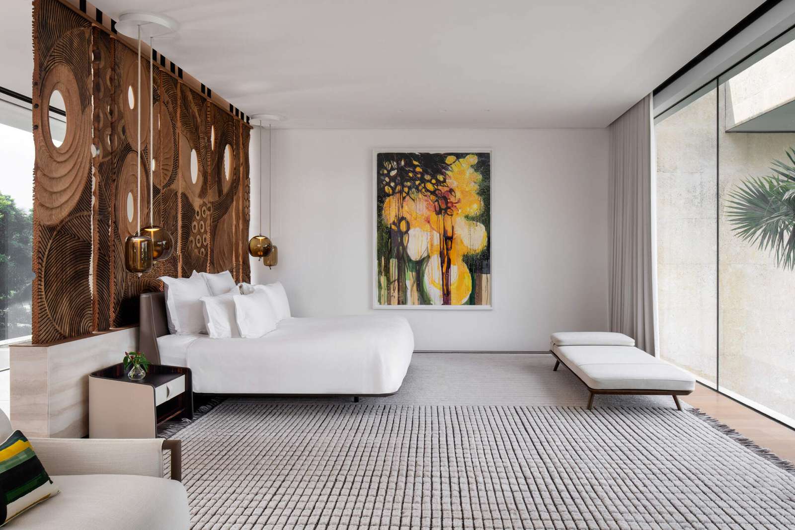 Interiors, like this bedroom, are filled with timber, stone, and local artwork create a warm contrast to the clean architecture.