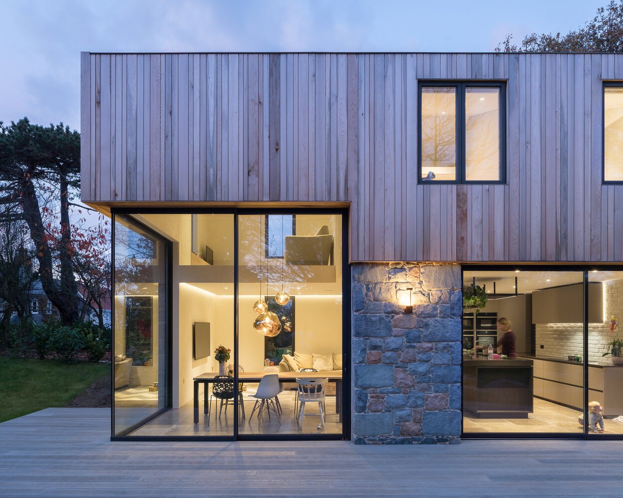 This modern home is wrapped in Guernsey granite, cedar cladding, and a living wall with 13 native species that soften the structure and blend it into the forested setting.