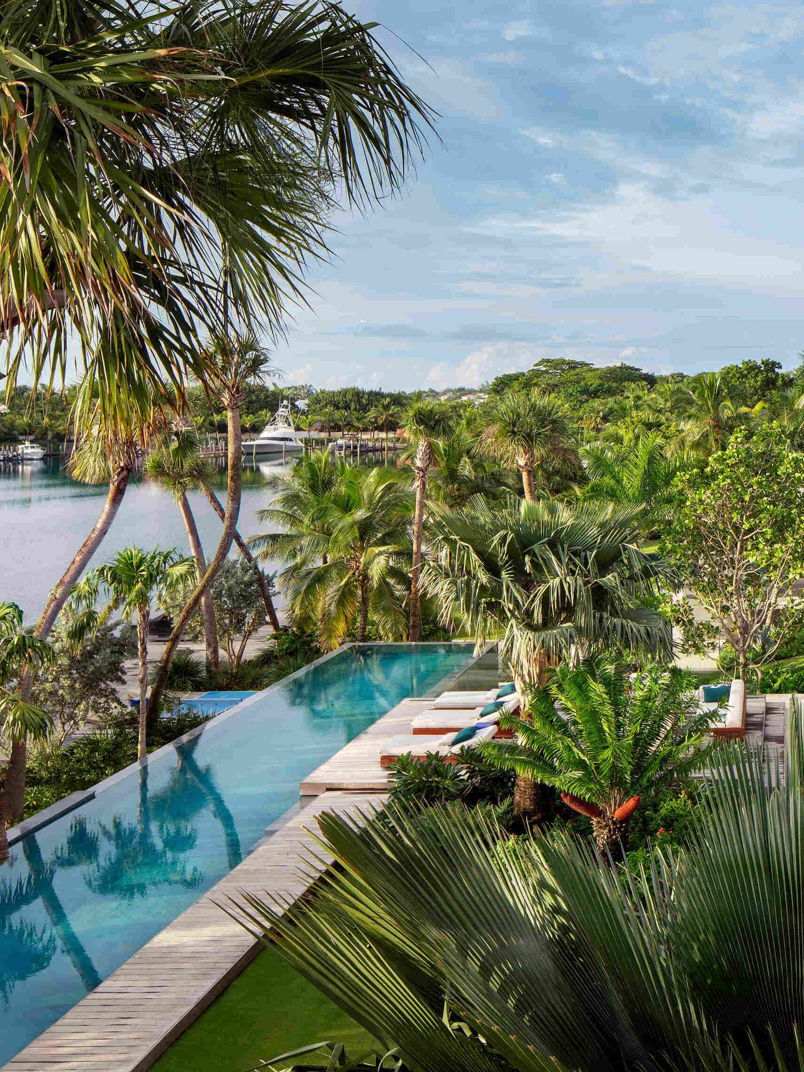 A tropical home with outdoor rooms and an infinity pool that blends naturally with the canal and surrounding greenery.