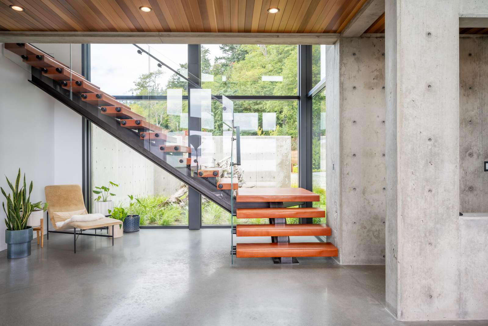 Located off the great room, the staircase is both functional and expressive. Exposed concrete and steel structure are paired with leather treads chosen by the clients, and a large light fixture adds a personal design gesture within the otherwise restrained interior.