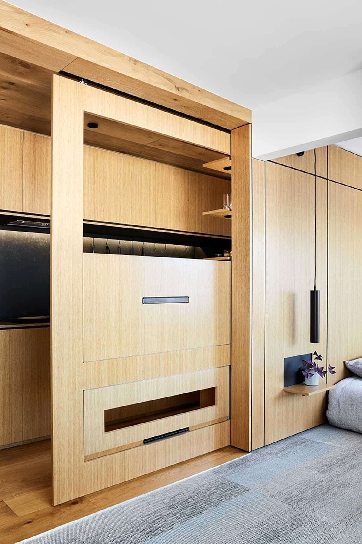 A fold-down dining table slides out from a hidden cavity, proving smart furniture can completely change how a small apartment functions.