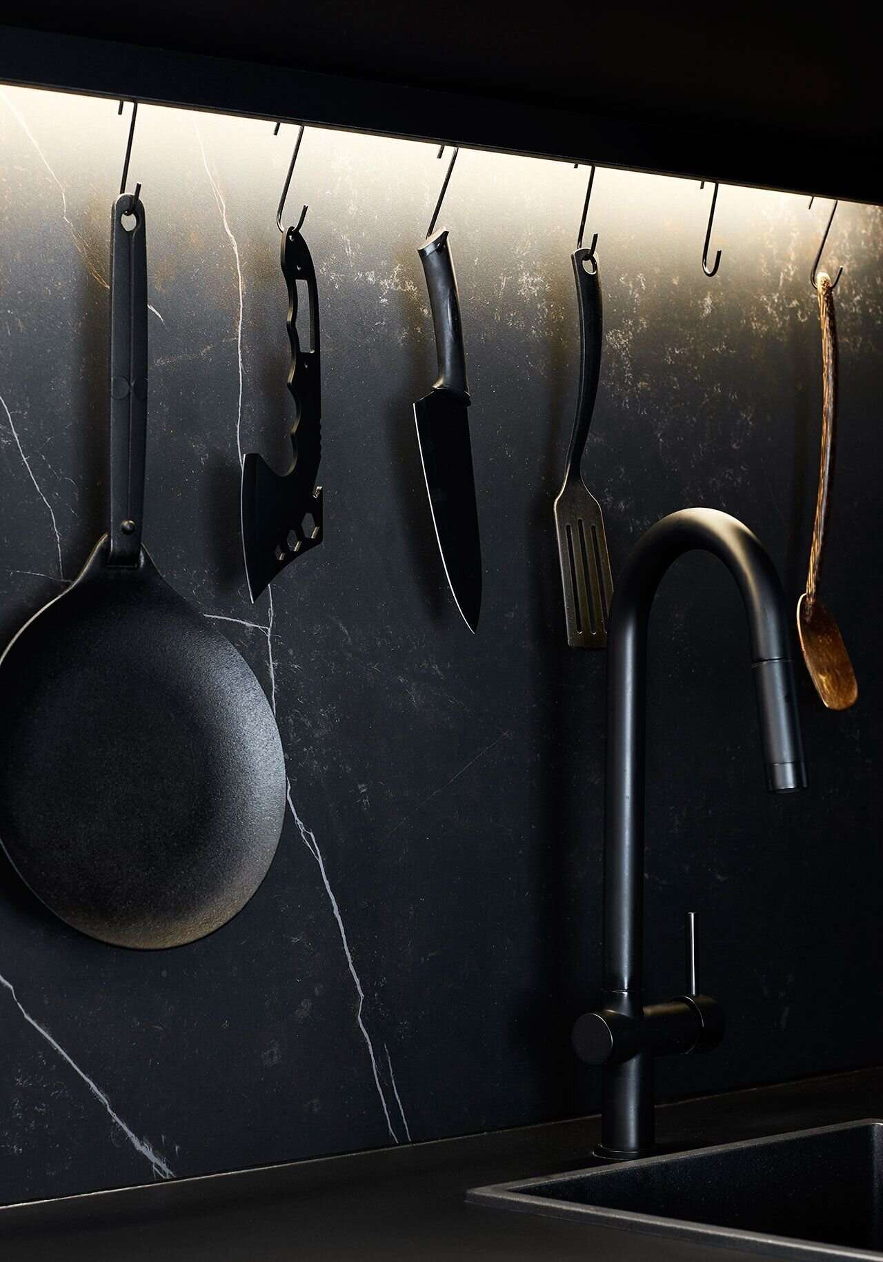 A long timber kitchen with black accents hides appliances and maximises bench space inside this compact Melbourne apartment.