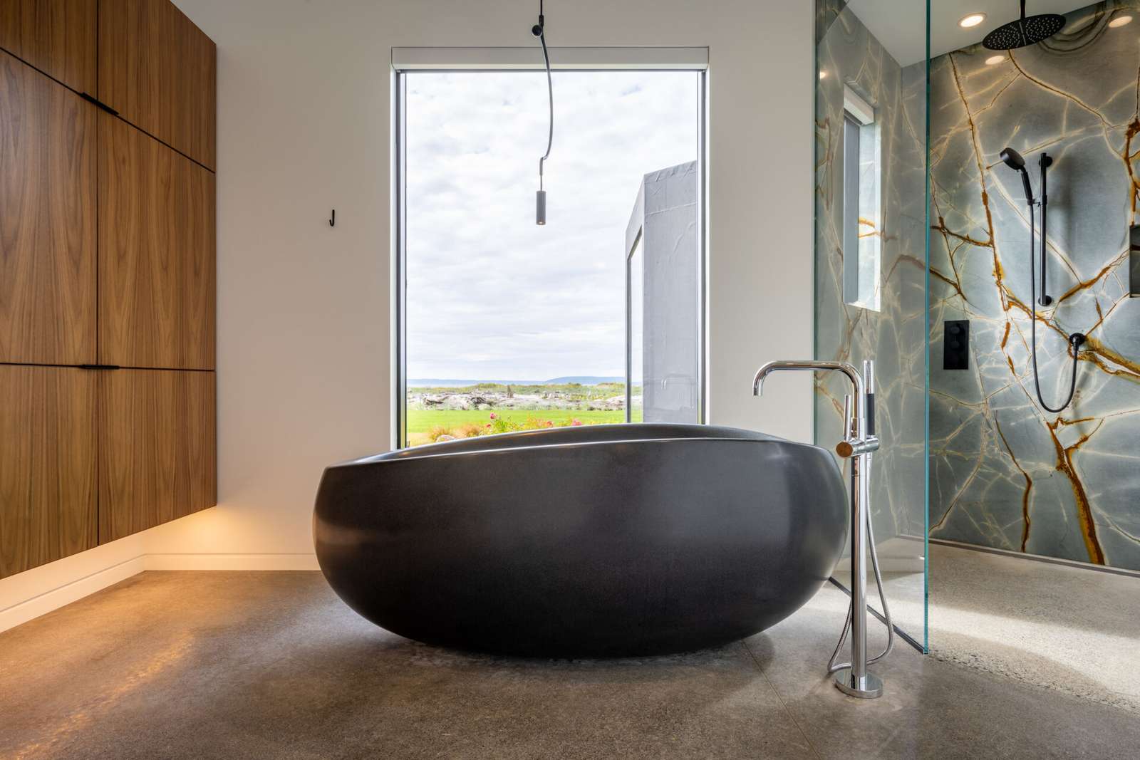 The primary bathroom includes a floating wood vanity with a freestanding sculptural black bathtub, and an eye-catching shower.