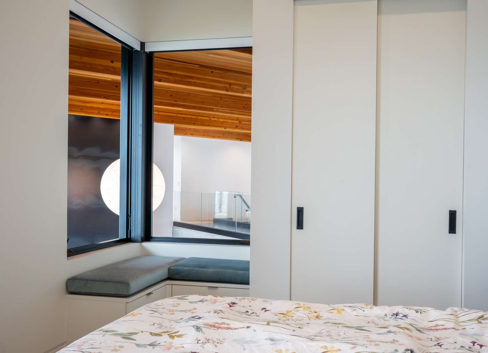 Bedrooms in a modern house have windows that look out to the water.