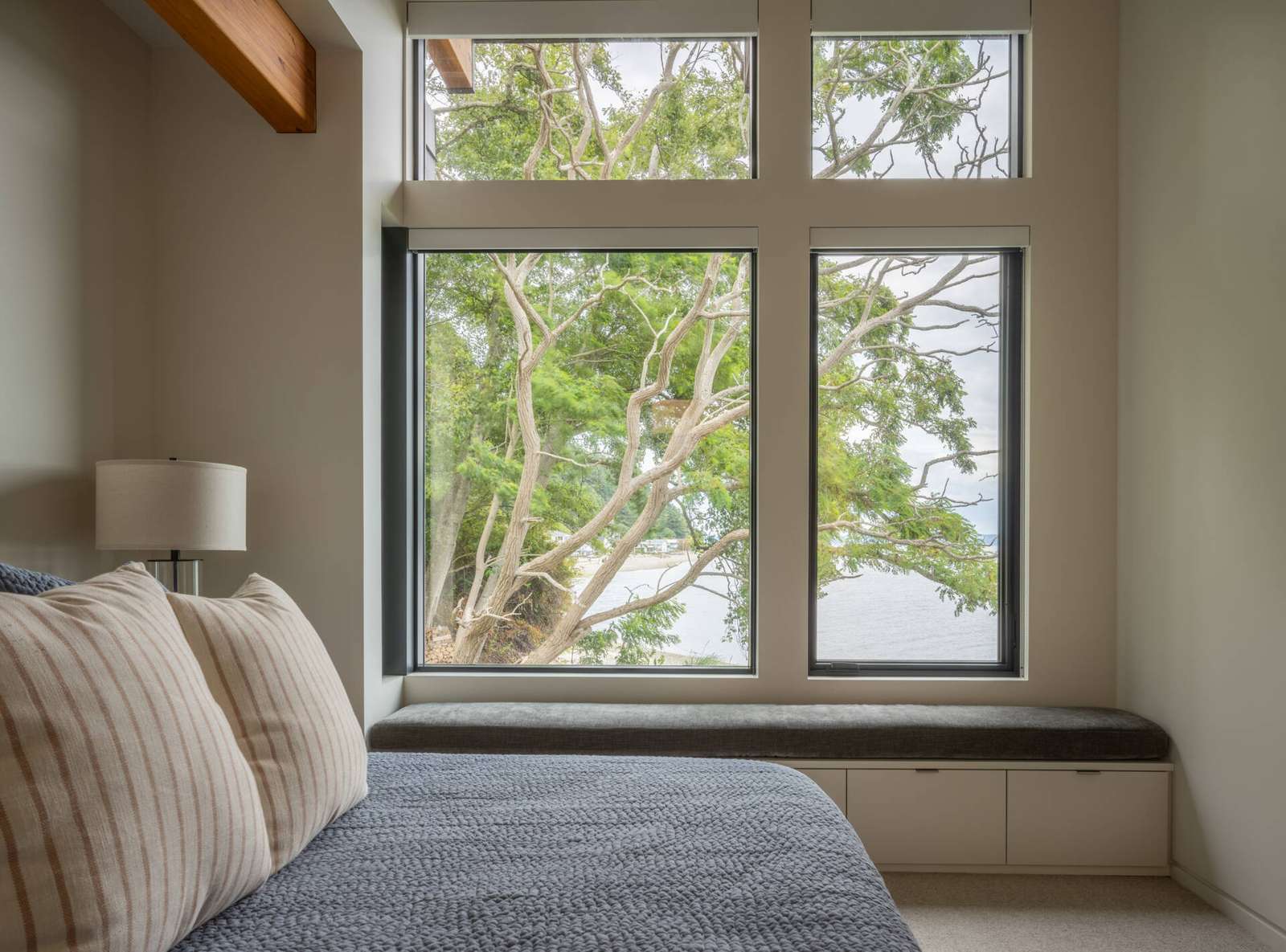 Bedrooms in a modern house have windows that look out to the water.