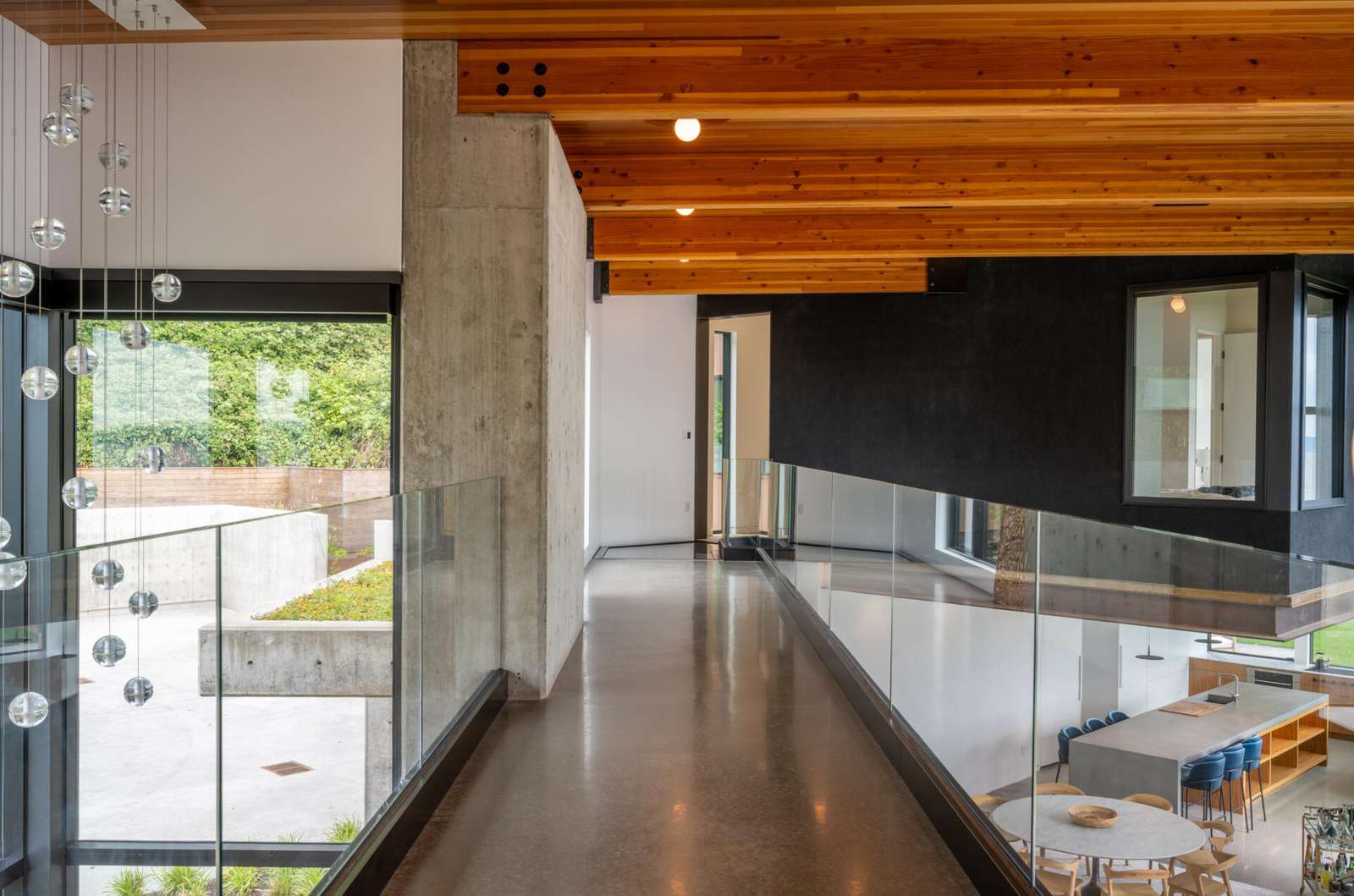 An interior bridge connects the north and south wings of this home. From this vantage point, the green roof above the entry becomes a prominent visual element. The bridge reinforces the sense of movement and connection throughout the home.