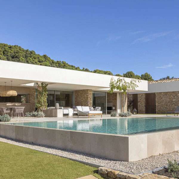 A modern house with stone walls that are highlighted by the use of both exterior and hidden lighting.