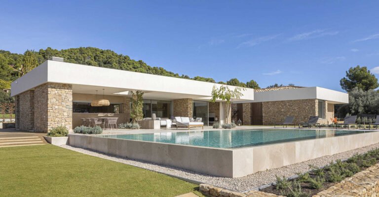 A modern house with stone walls that are highlighted by the use of both exterior and hidden lighting.