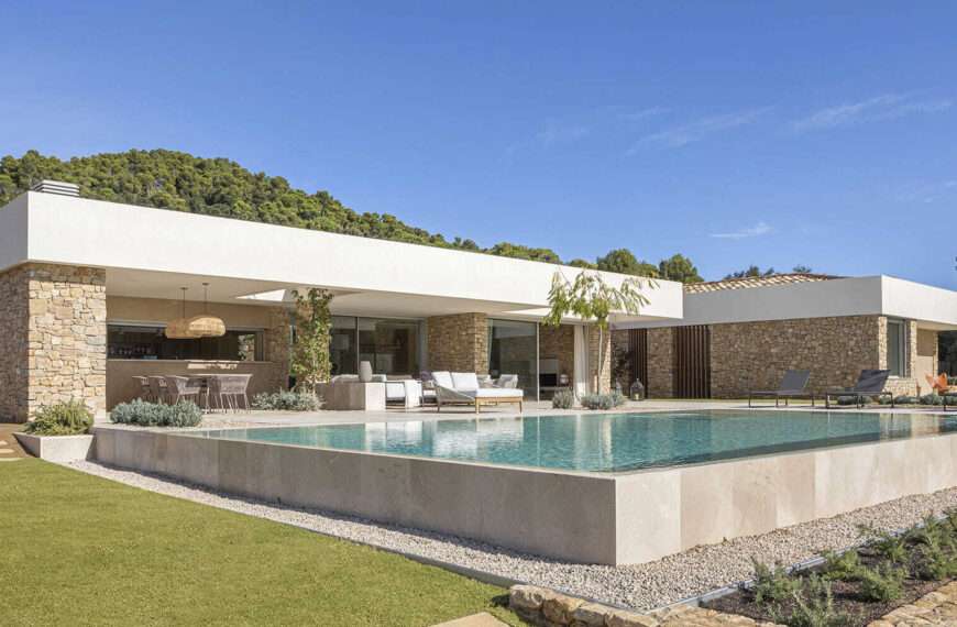 A modern house with stone walls that are highlighted by the use of both exterior and hidden lighting.