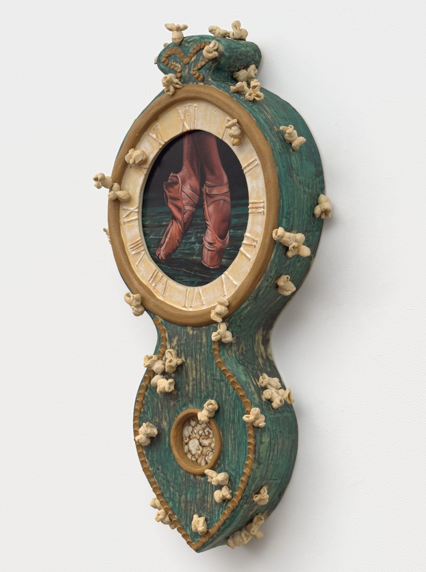 a ceramic sculpture by Stephanie Temma Heir shaped like a clock and covered in popcorn. a painting of ballet shoes sits at the center