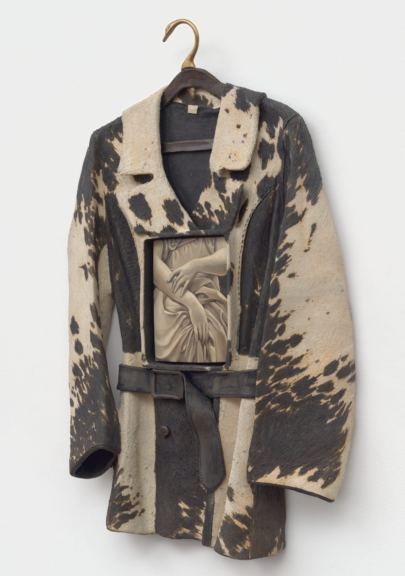 a ceramic sculpture by Stephanie Temma Heir featuring a cowprint jacket on a swan shaped hanger. a painting of hands grasping a skirt is embedded in its front