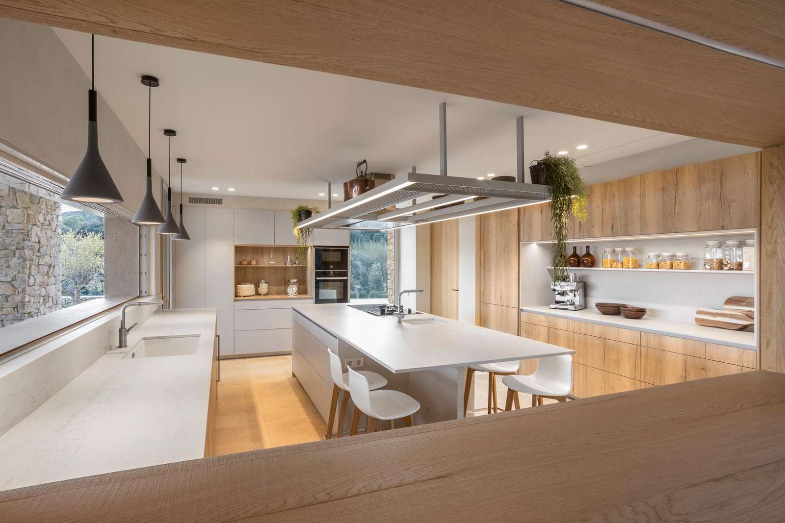 In this kitchen, minimalist white cabinets and countertops are paired with wood cabinets and shelves, and a central island to create a modern appearance.