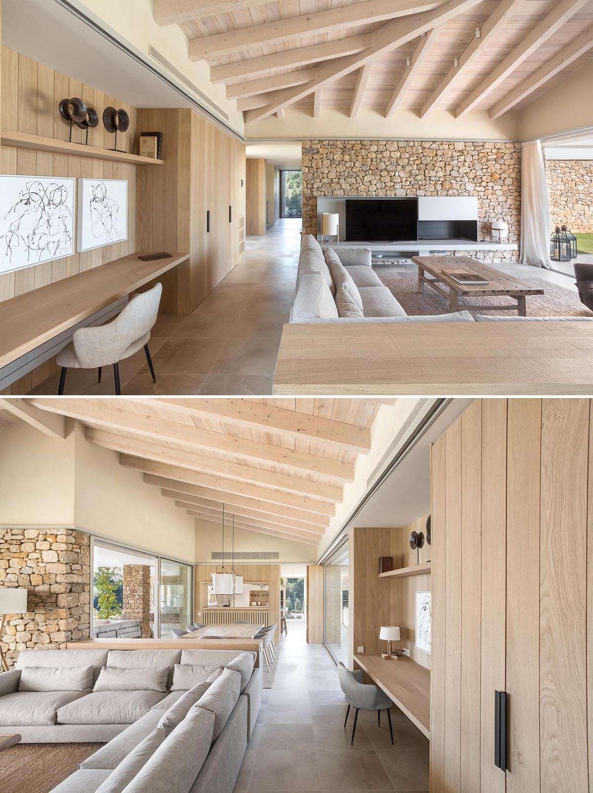 This modern house has stone walls and an open plan living room and dining room, that also includes home office that's built along a wood wall. 