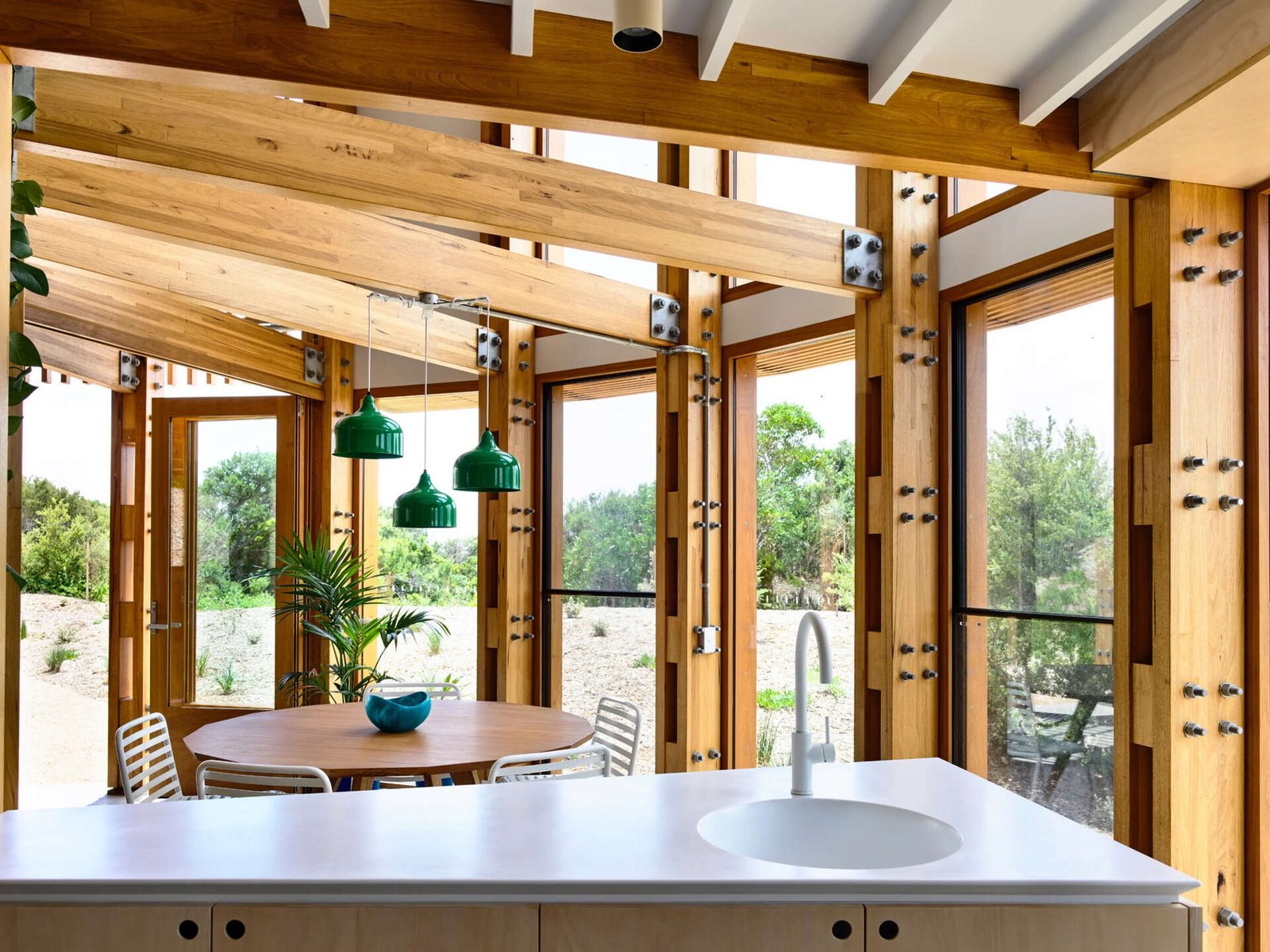 Open plan kitchen, dining and living areas inside a compact circular beach house designed for shared living.